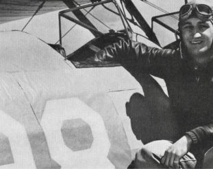 Tom Harmon sits on the wing of his plane